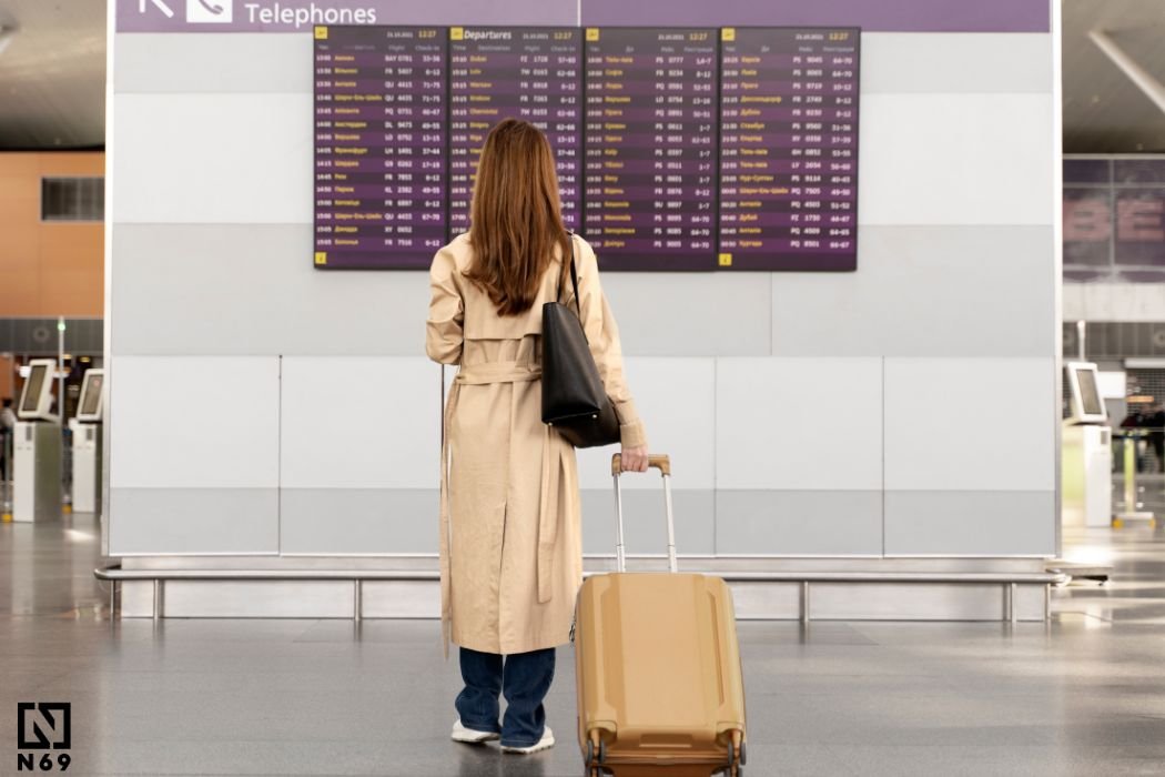 kobieta z walizka przed tablicą odlotów