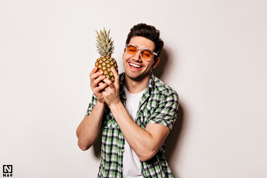uśmiechnięty mężczyzna trzymający ananasa